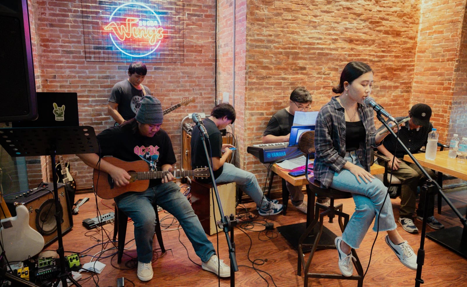Members of the Full Scale music club performing live together, on guitar, keys, cajon and vocals