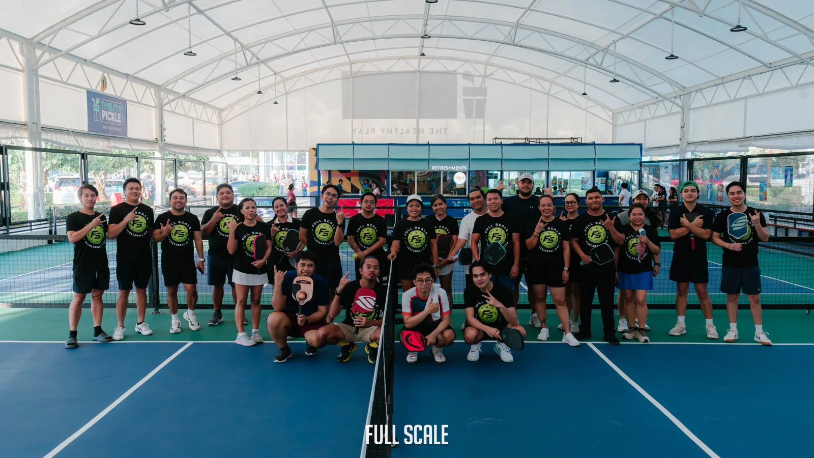 The Full Scale pickleball club, about twenty employees in matching club shirts, gathered on court after a company tournament