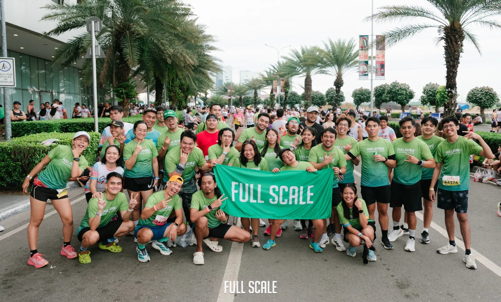 The Full Scale running club holding a company banner together at a public marathon
