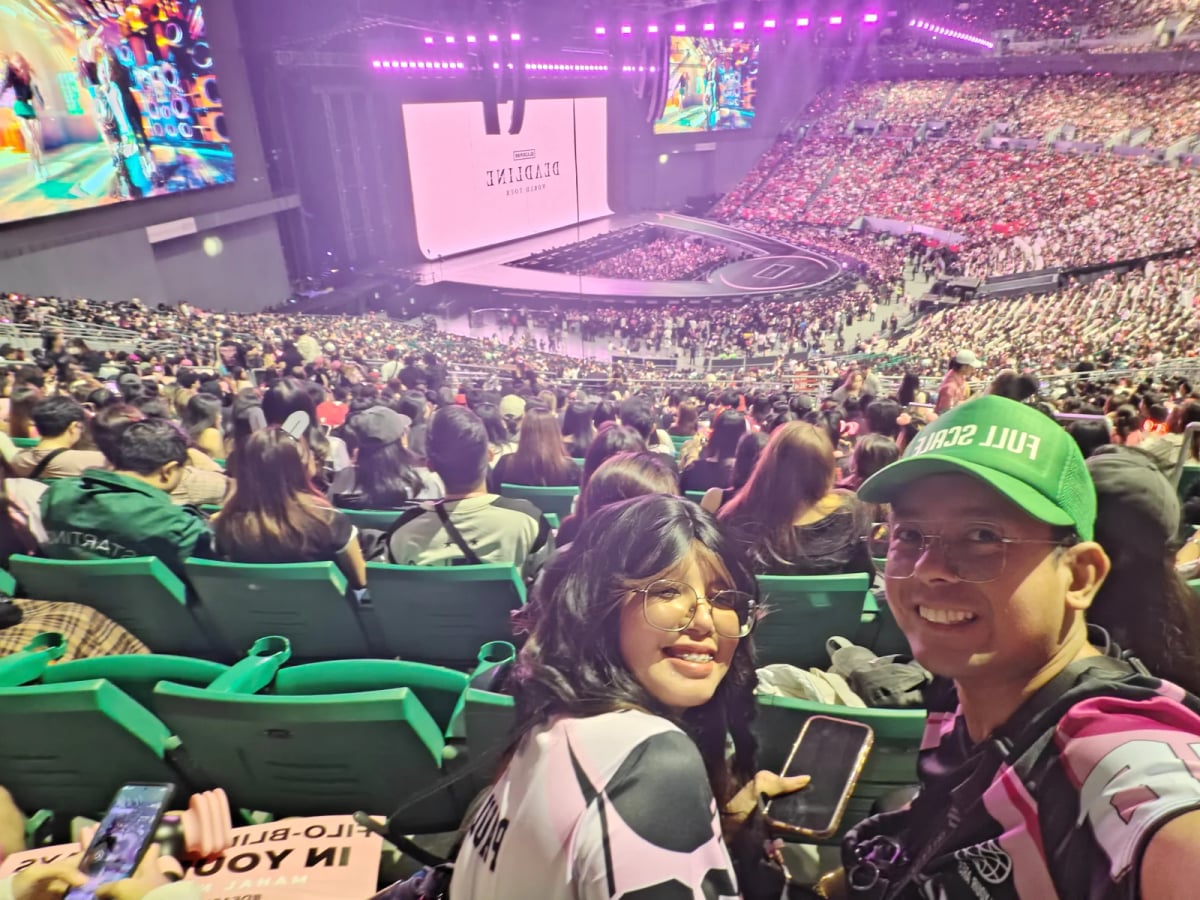 Two Full Scale employees at the BLACKPINK concert with the packed Philippine Arena behind them