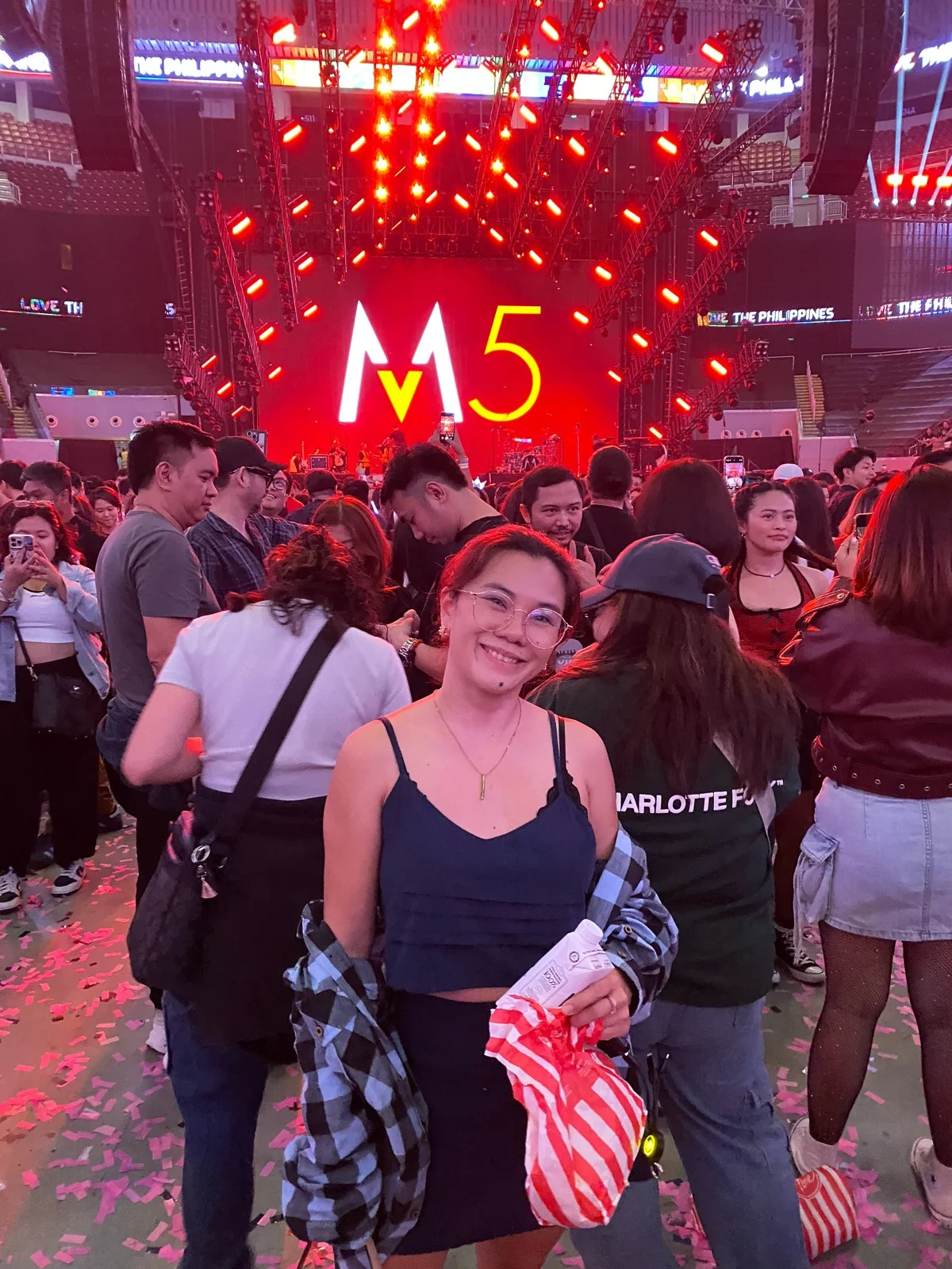 A Full Scale employee at the Maroon 5 concert, floor confetti and the illuminated M5 stage screen behind her