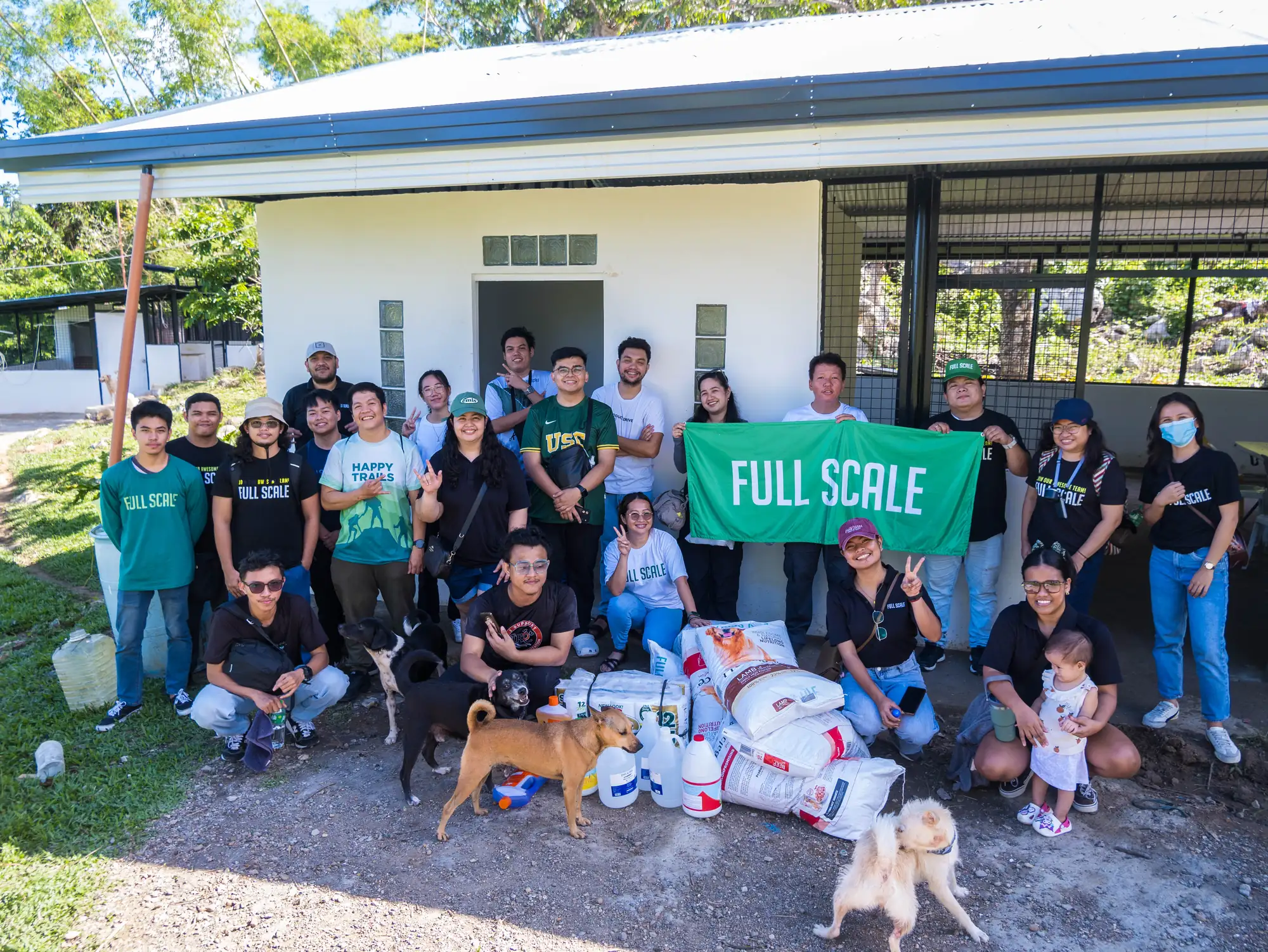 Full Scale volunteers with the company banner, donated supplies, and rescued dogs at Island Rescue Organization